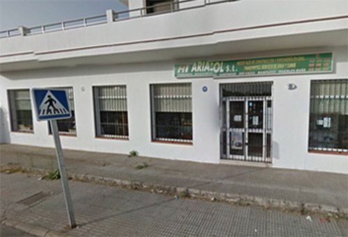 Un edificio blanco con una señal de cruce de peatones azul delante.