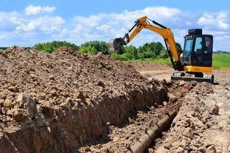 Una excavadora amarilla está cavando una zanja en la tierra.