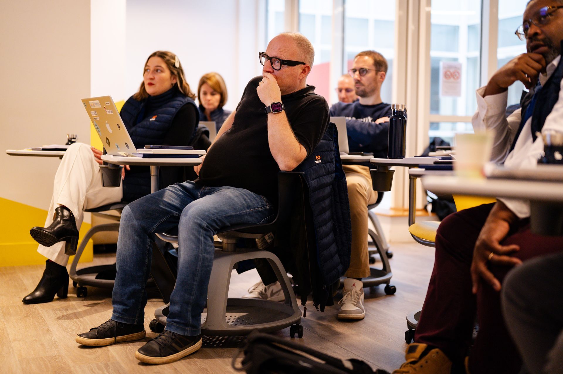 Des personnes assises dans une salle moderne et lumineuse, assistant à une présentation ou à un atelier.