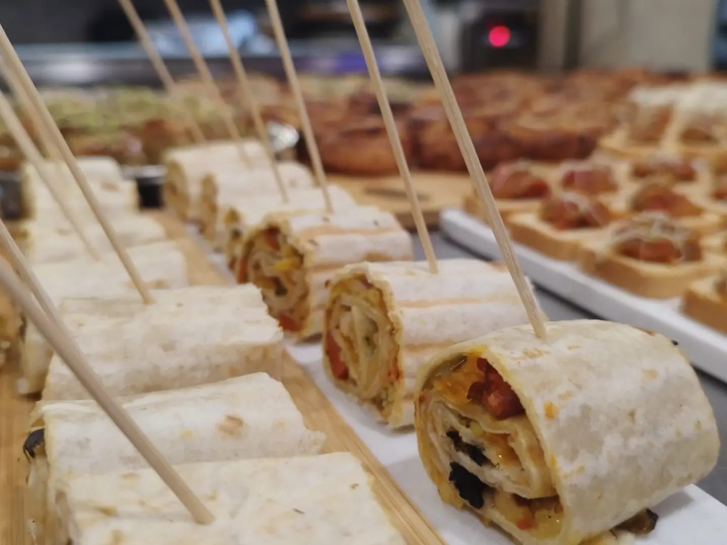 Una fila de tortillas envueltas con palillos de dientes sobresaliendo de ellas
