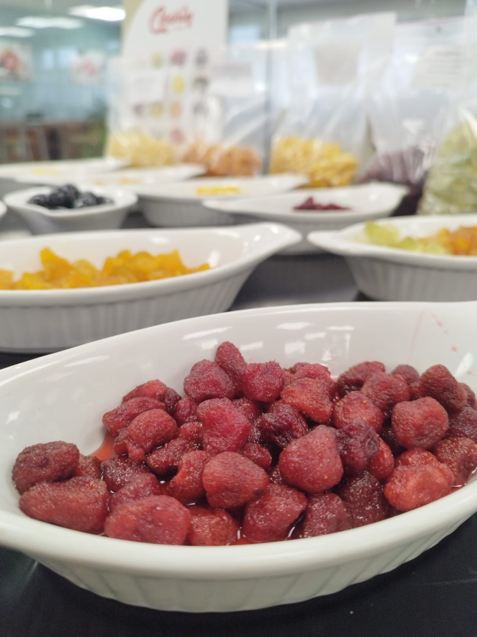 Un tazón blanco lleno de frambuesas se encuentra sobre una mesa.