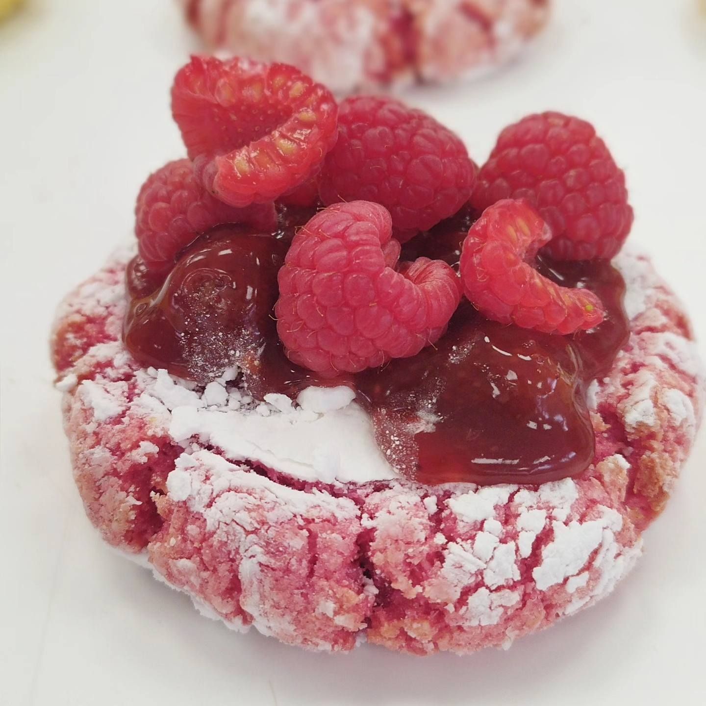 Una galleta con frambuesas y azúcar glas encima.