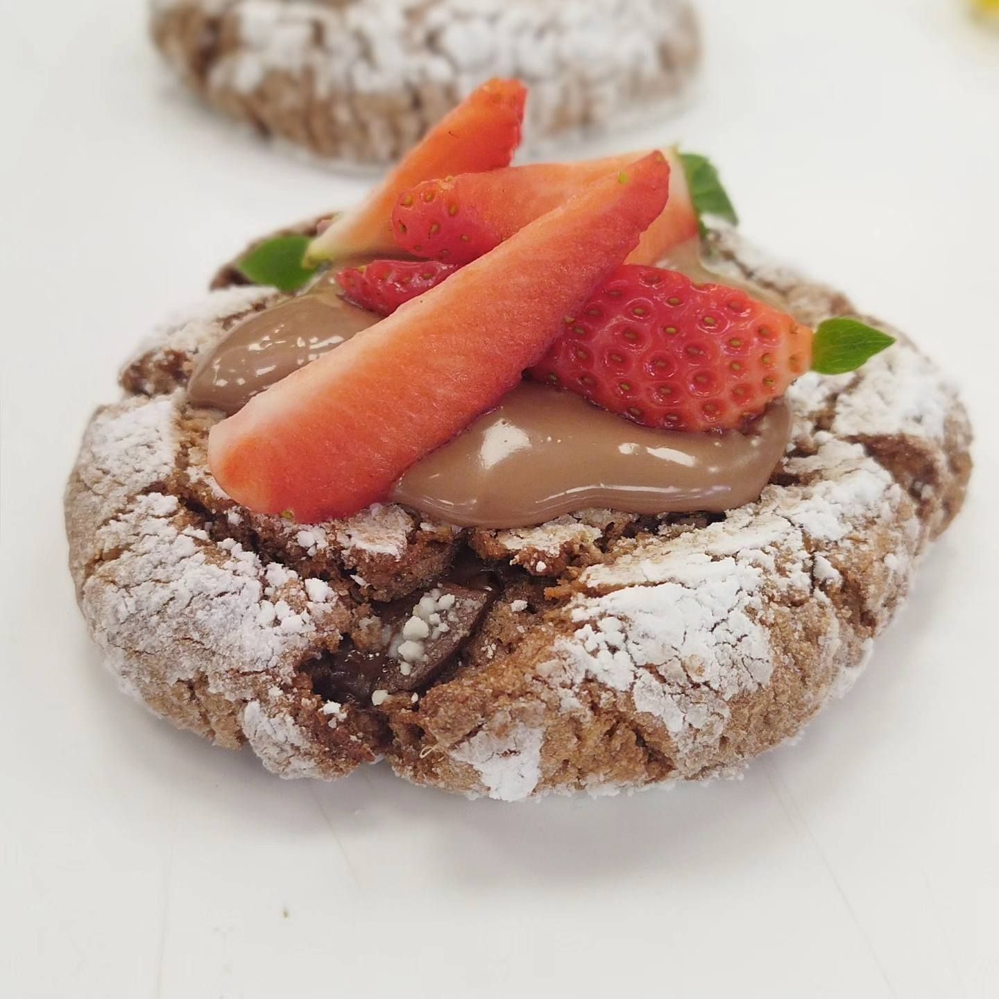 Una galleta con azúcar glas y fresas encima.