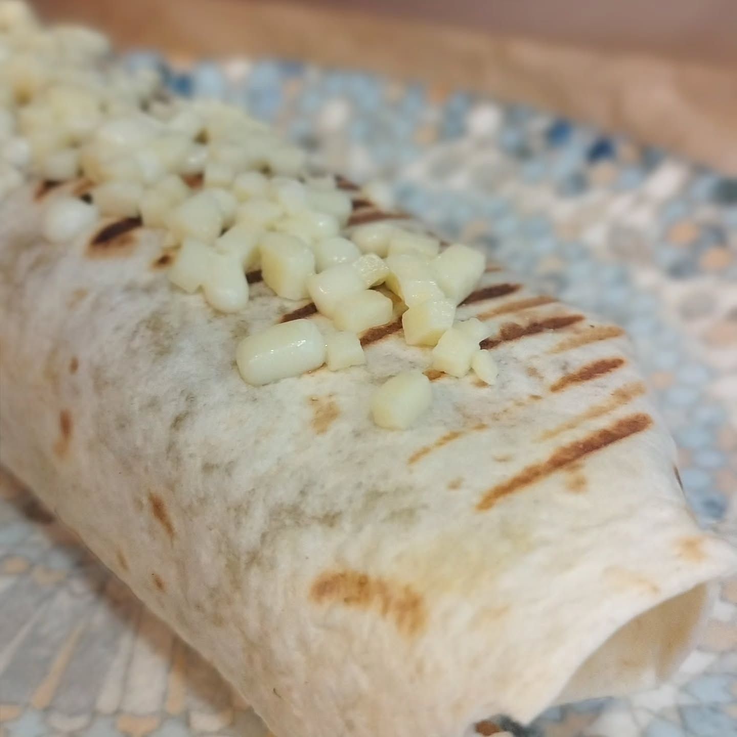 Un burrito con queso encima en un plato.