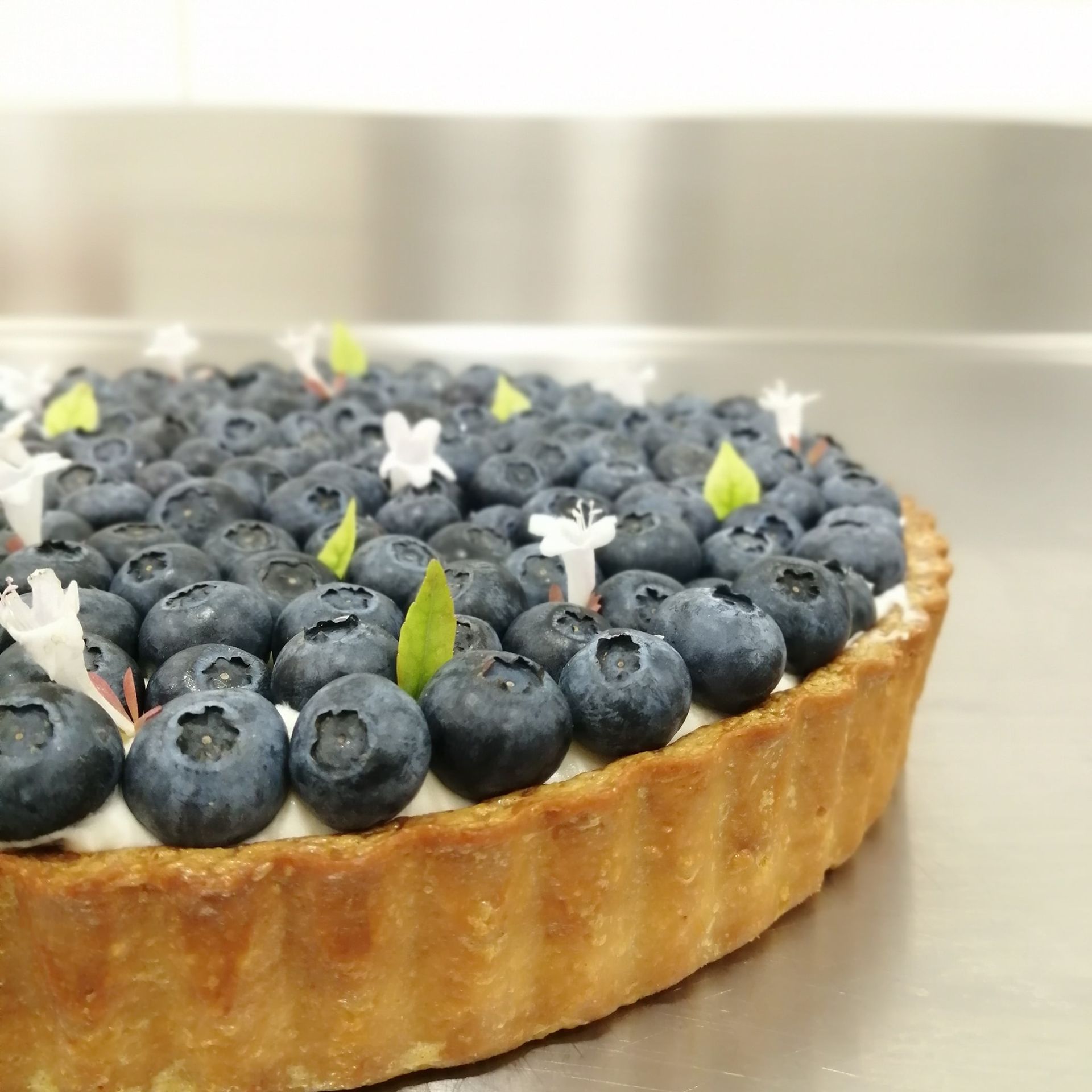 Un pastel con arándanos y flores encima.