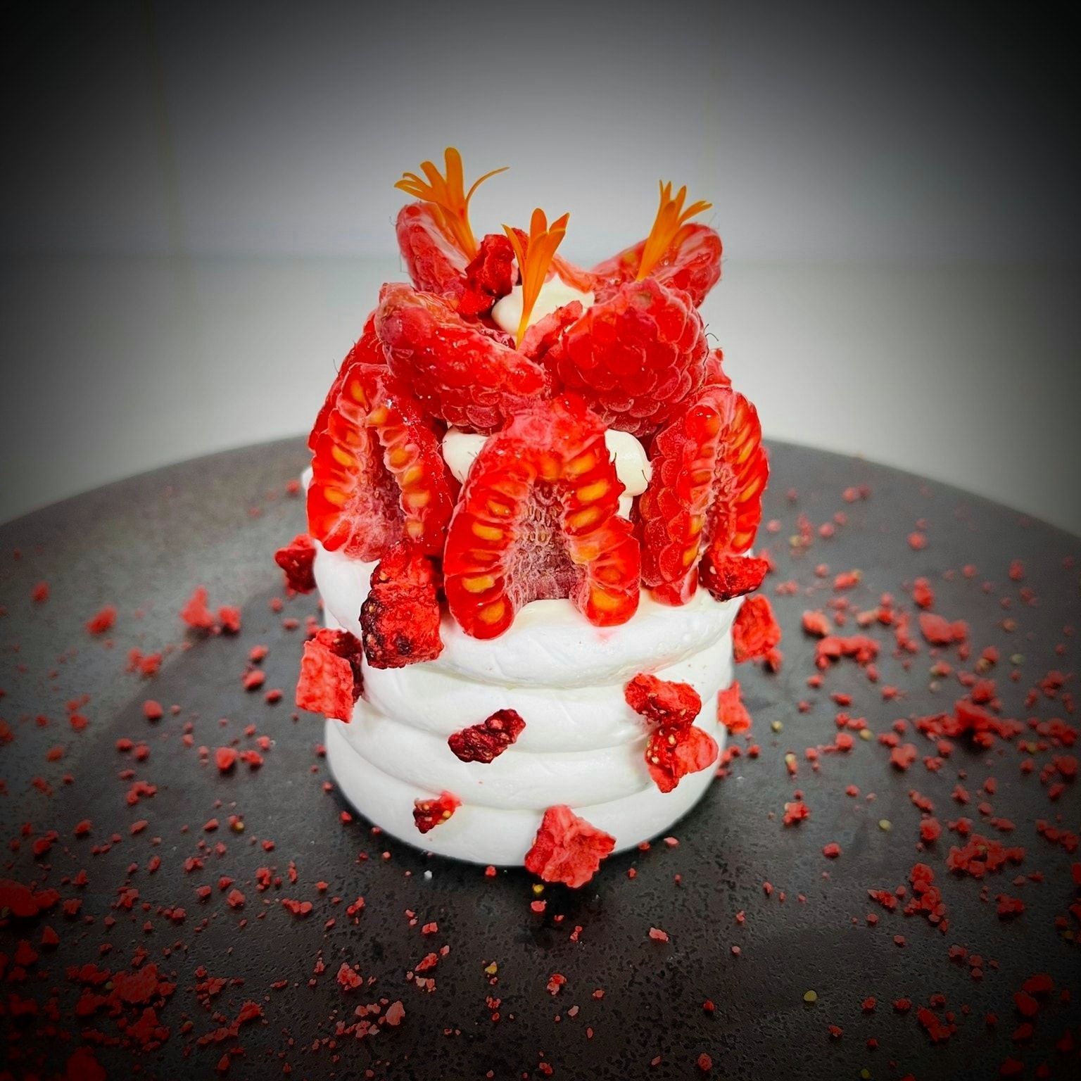 Un pequeño pastel con fresas encima en un plato negro.