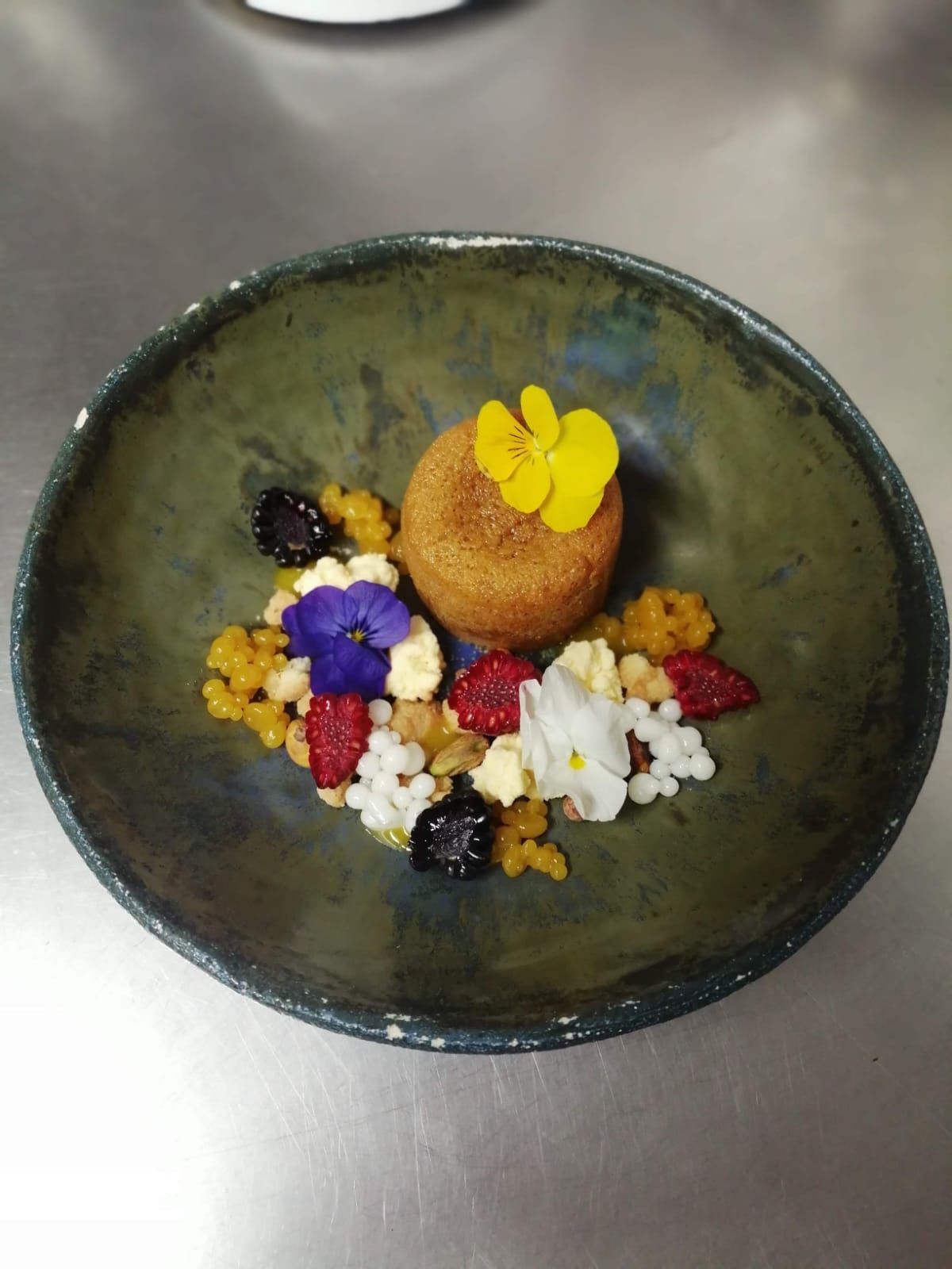 Un postre en un bol verde: un pastel con flores y migas de colores.