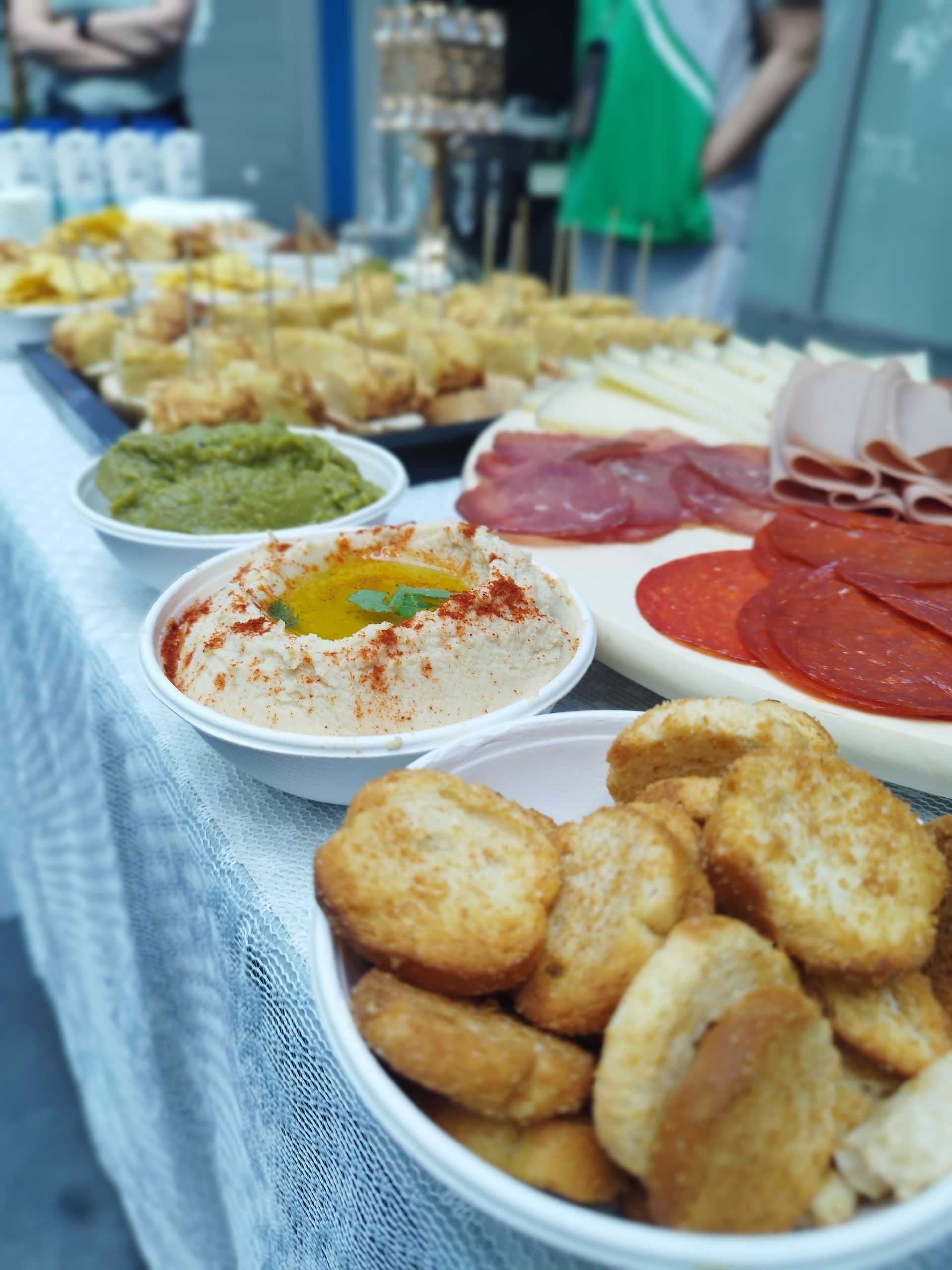 Una mesa repleta de aperitivos que incluyen hummus, carnes, pan y salsas.