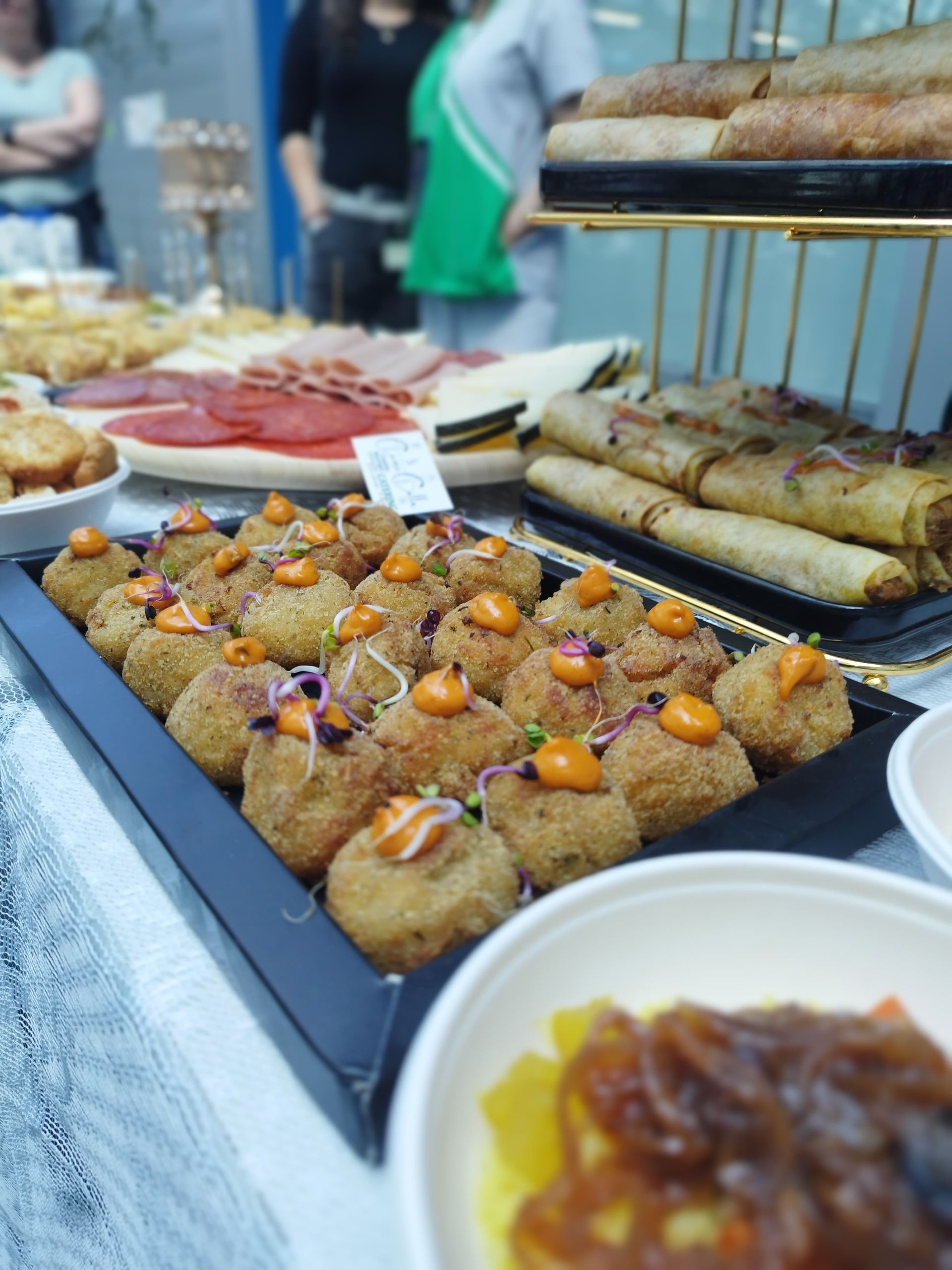 Exhibición de comida en un mercado: aperitivos fritos, jamón, pasteles y otros artículos, una mesa llena.