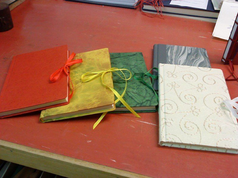 Fünf bunte Ringbücher in den Farben Orange, Gelb, Grün, Grau-Weiß und Weiß.