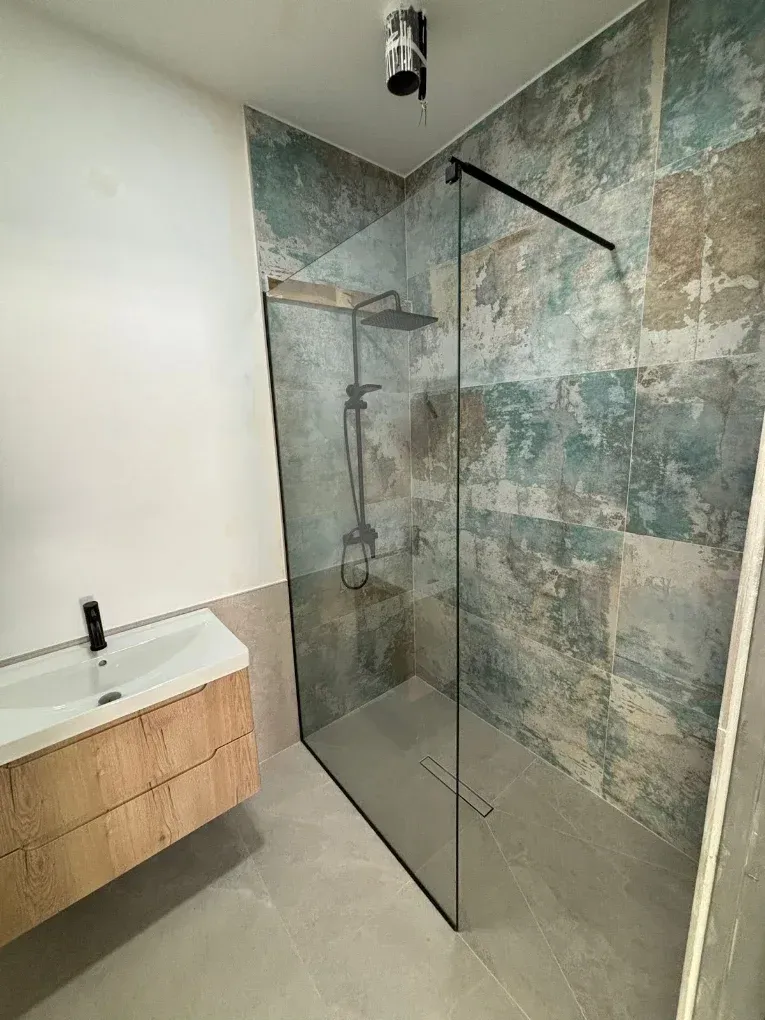 Una persona instala un cristal en una casa de ladrillo rojo, sosteniendo un panel de vidrio junto a una ventana abierta.