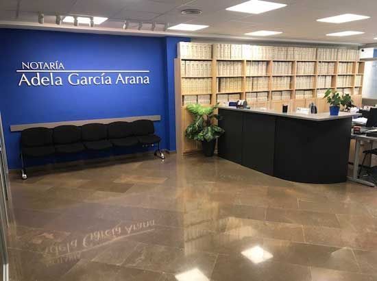 Una sala de espera con un cartel que dice notaria adela garcia arana
