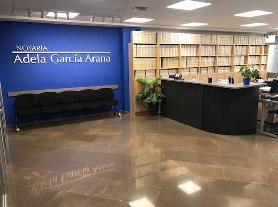 Una sala de espera con un cartel que dice notaria adela garcia arana