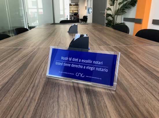 Una mesa de conferencias de madera con un cartel azul encima.