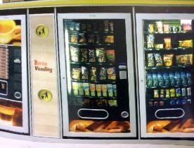 Máquinas expendedoras: Café, aperitivos y bebidas. Marcos negros, productos retroiluminados y botones. Detalles en amarillo y marrón.