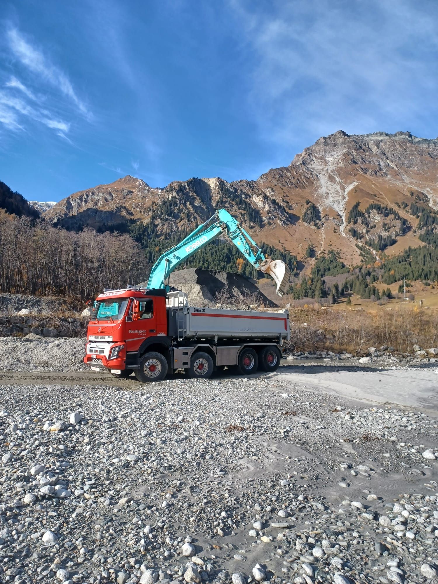 Ein Müllwerker leert einen Container in den Trichter des Lkw. Oranger Lkw und Uniform, Stadtkulisse.