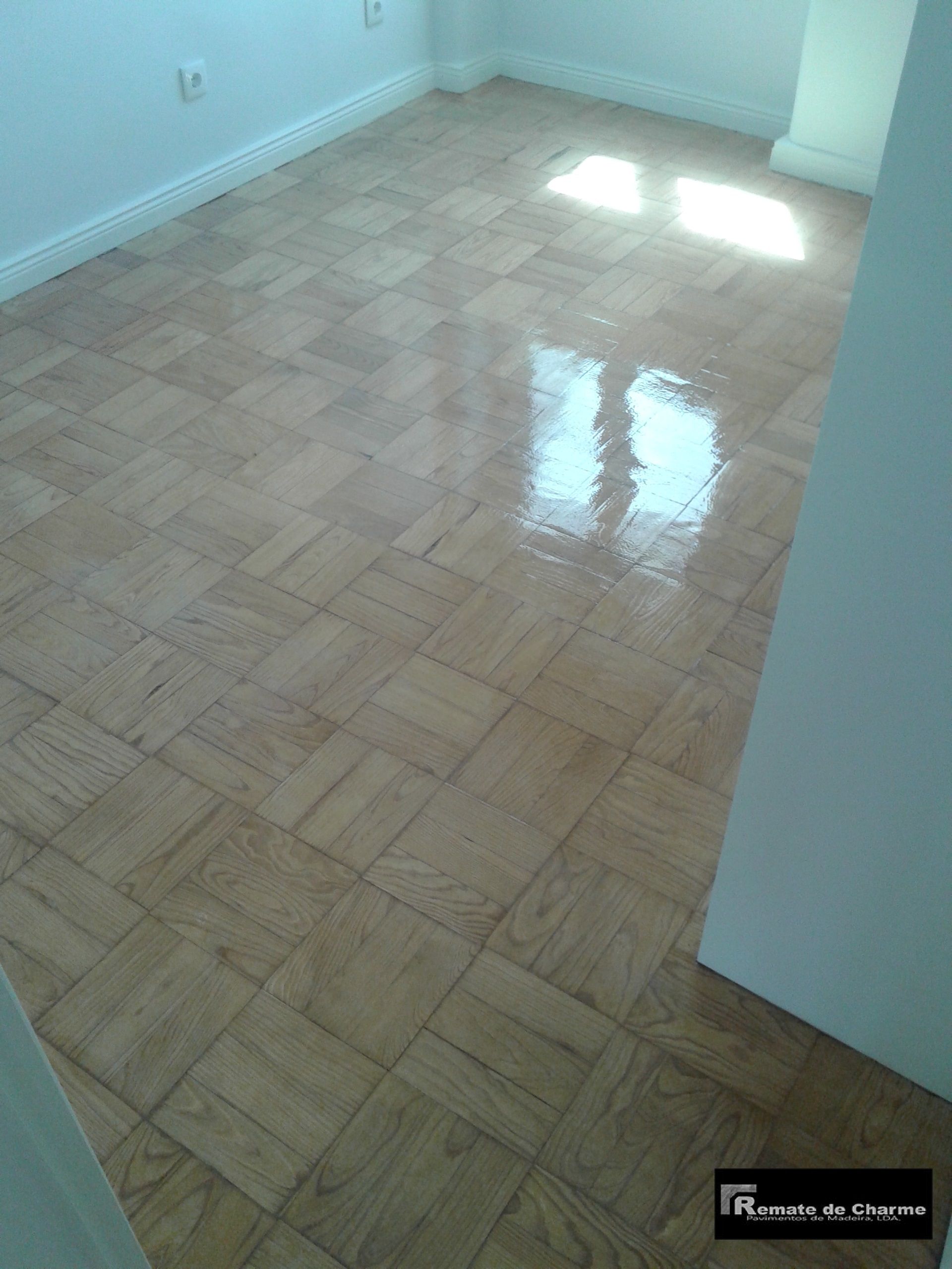 Piso de parquet de madeira em uma sala com luz natural brilhando, destacando a superfície polida.