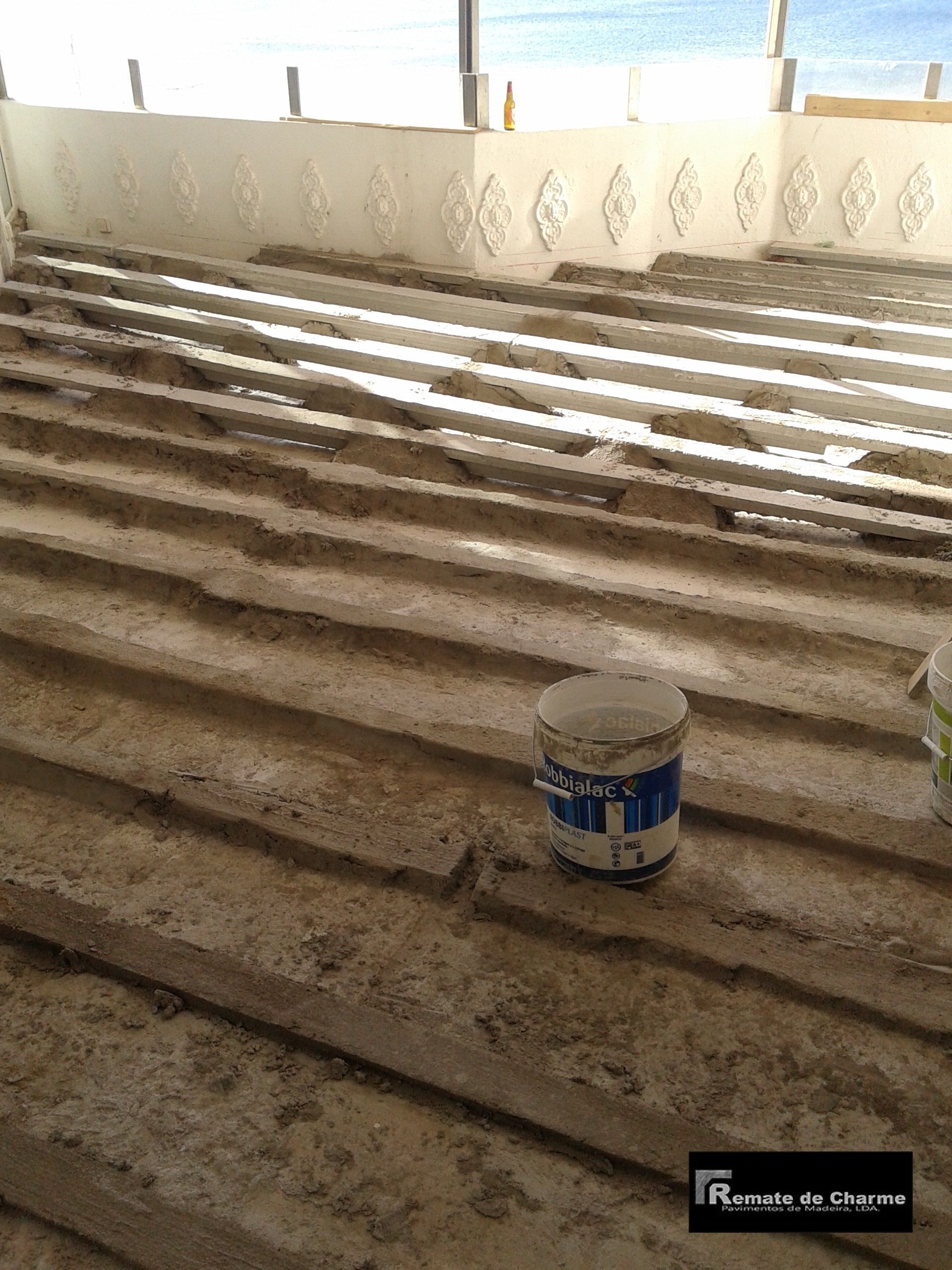 Degraus de concreto em construção, com um balde de tinta no meio. Cenário interno.