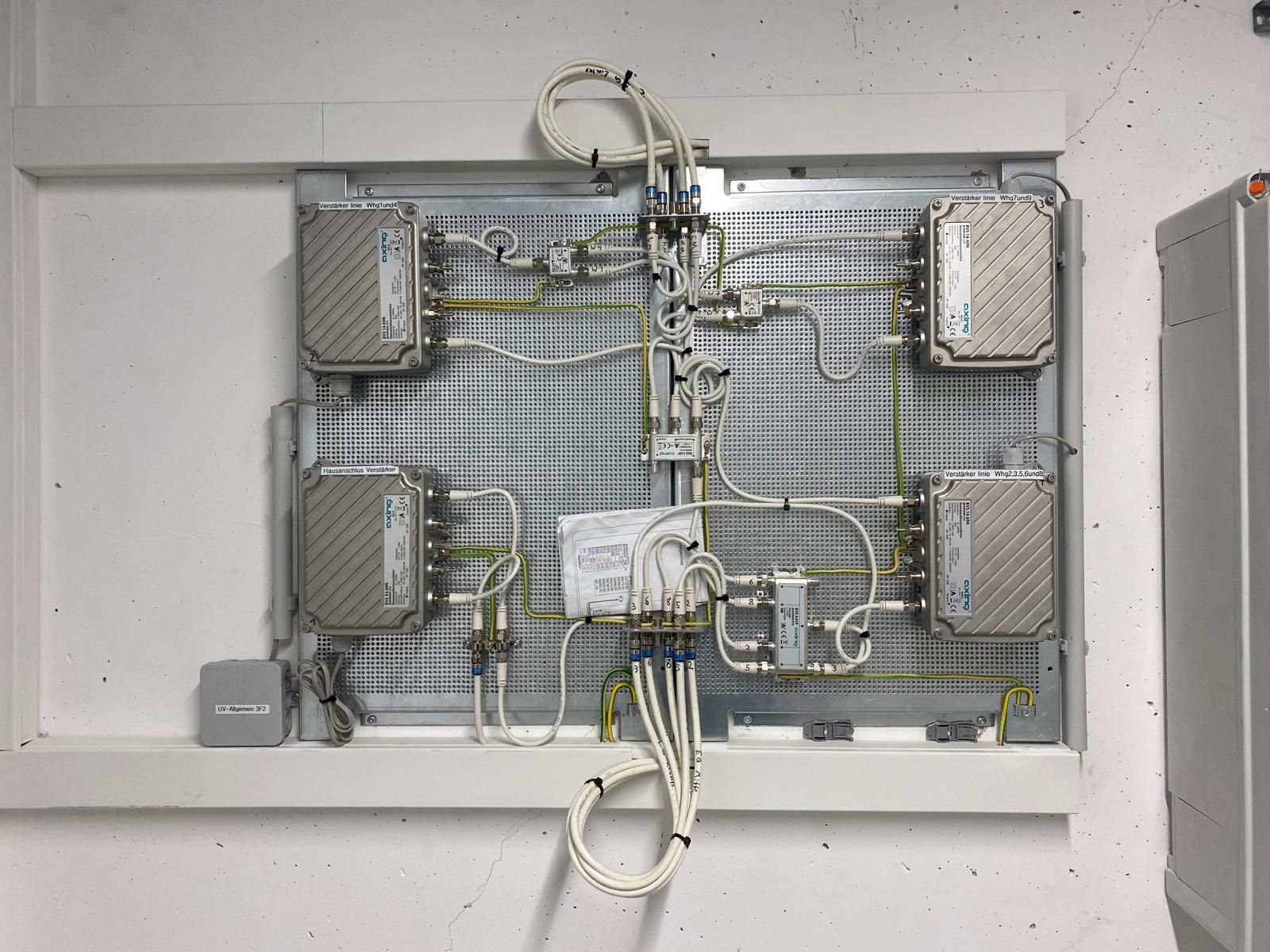 Antennenanlage mit vier silbernen Metallgehäusen, die durch weiße Kabel und Drähte verbunden sind.