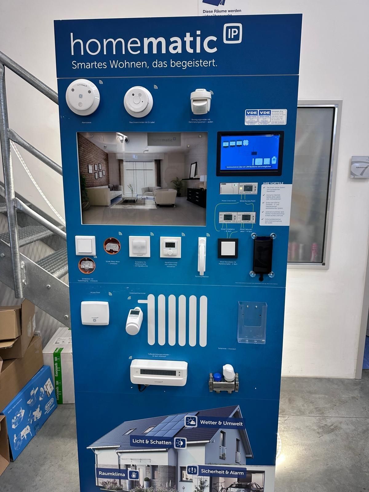 Ein blauer Homematic IP Smart-Home-Kiosk mit verschiedenen montierten Hausautomatisierungssensoren und -steuerungen.