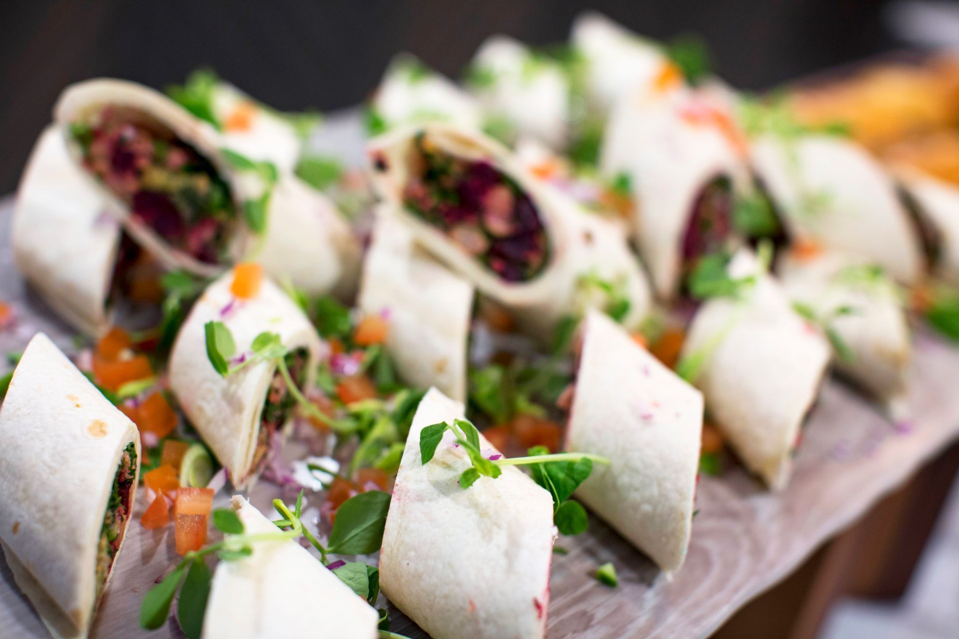 Wraps sliced and arranged on a wooden board, garnished with herbs and colorful salsa.