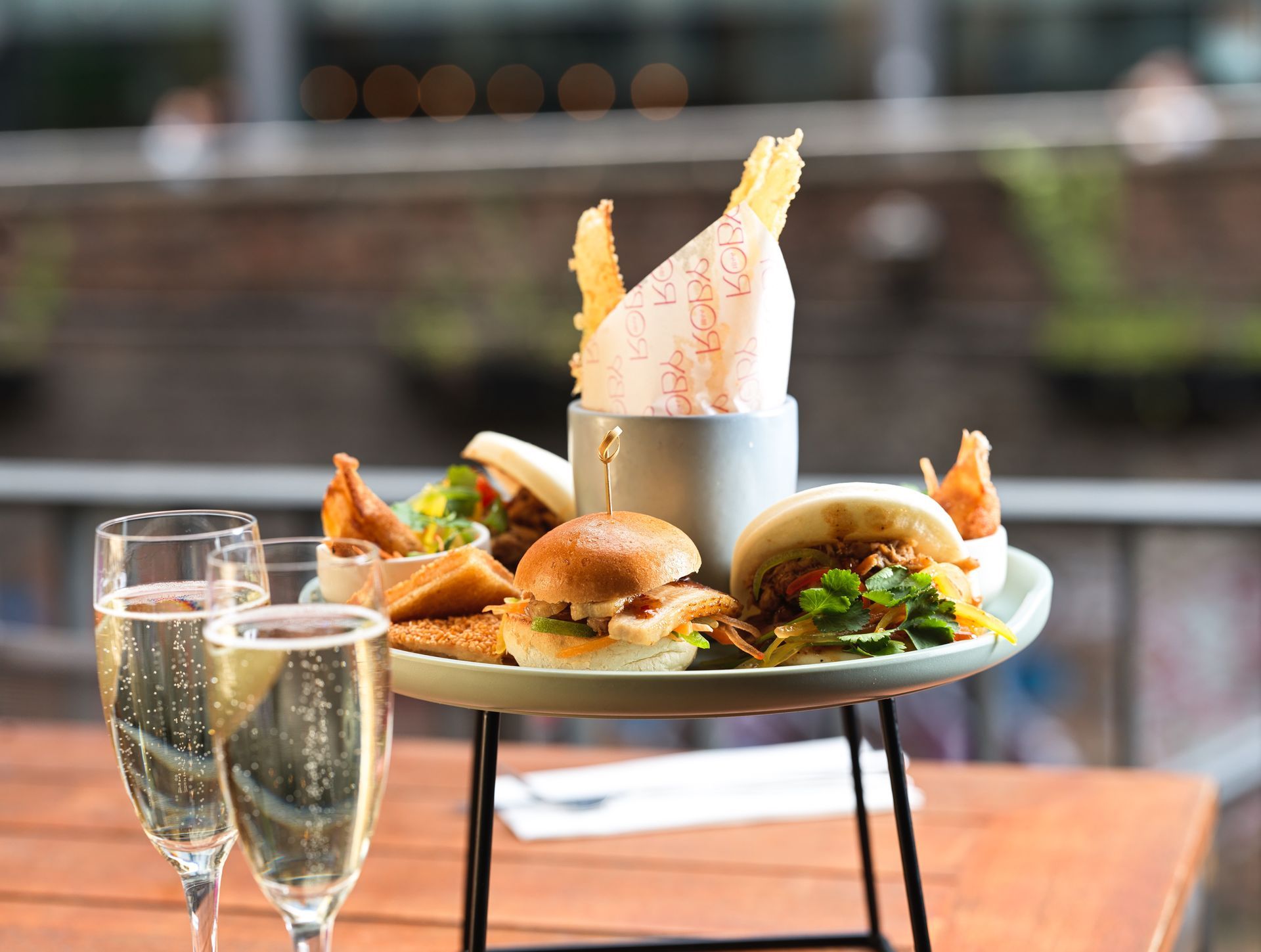 a plate with different burgers and fingerfood, two glasses with a drink in front of it