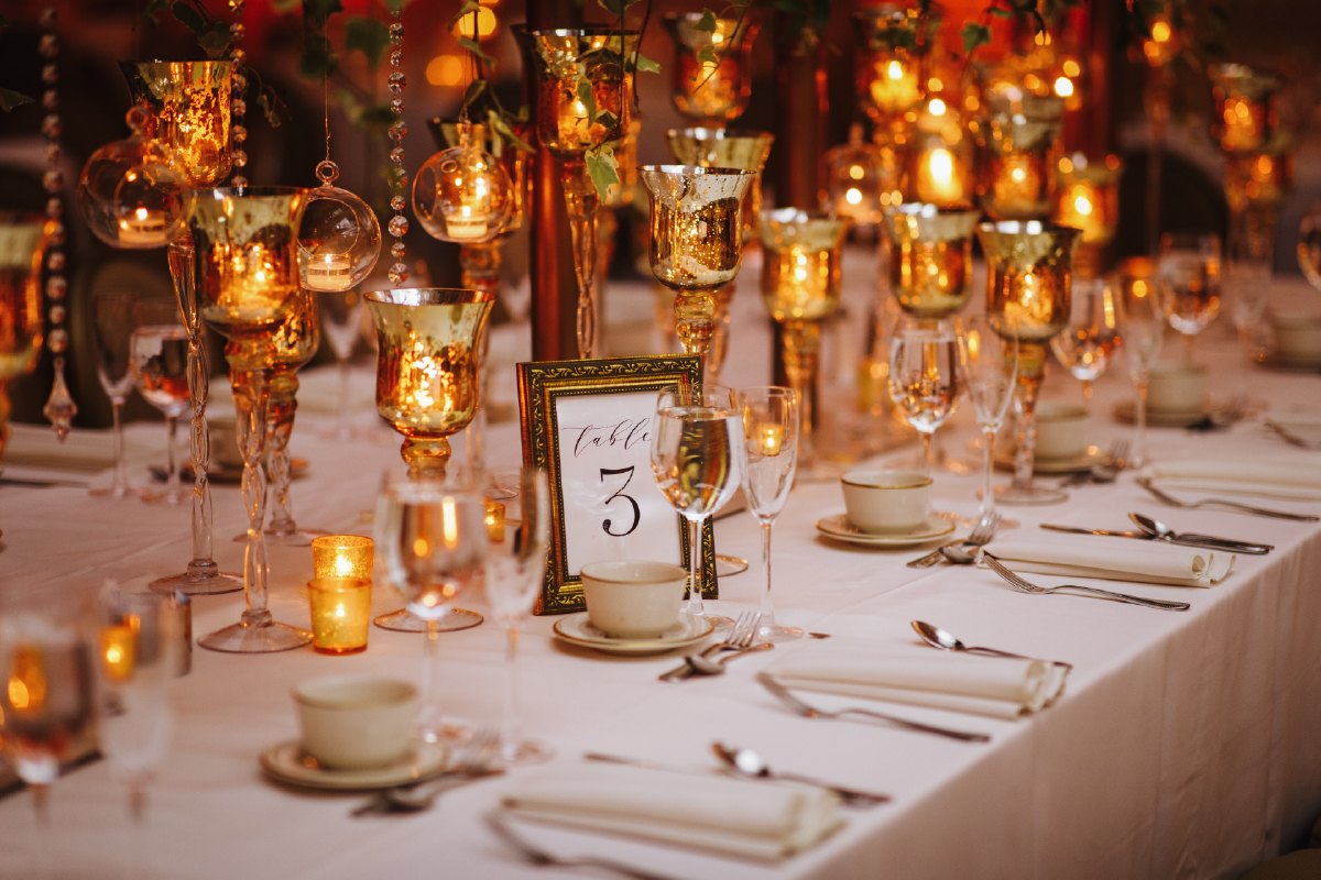 Elegant table setting with candles and floral decorations, lit with warm orange glow.