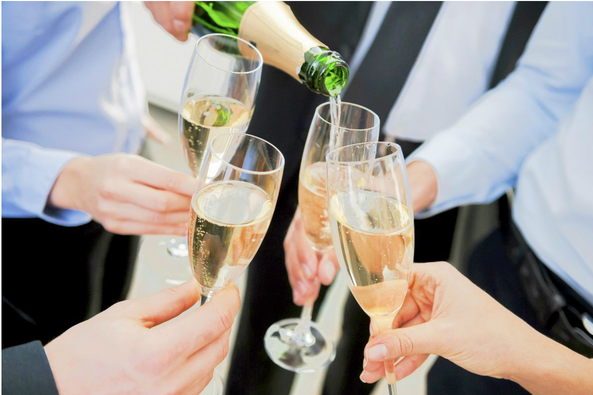 People toasting with champagne, as one person pours from a bottle.