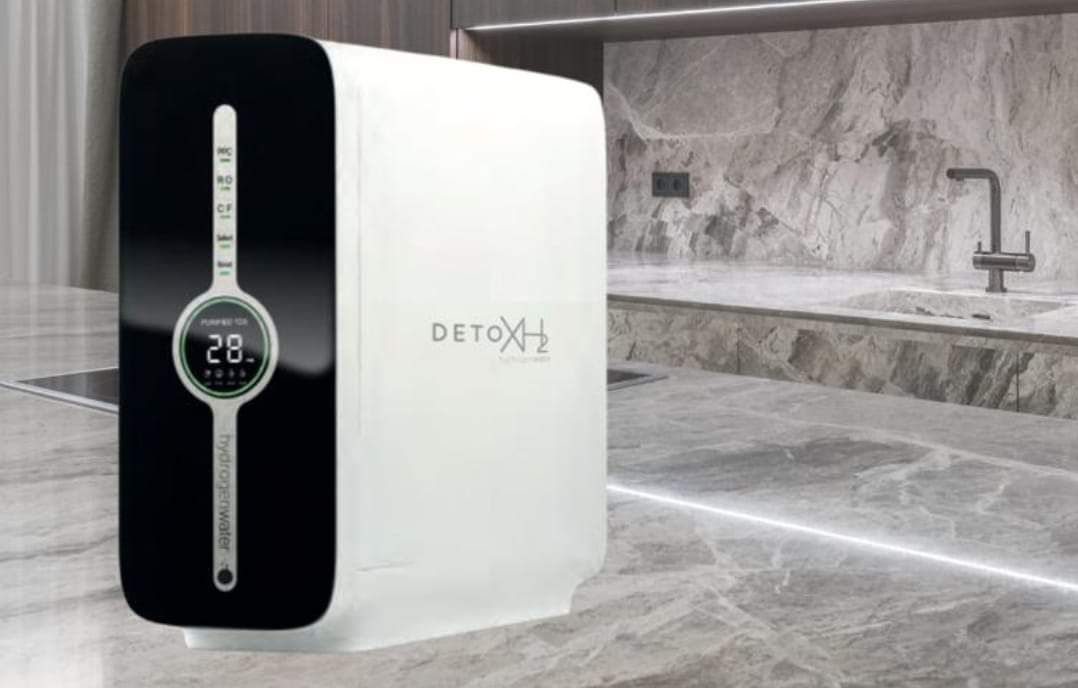 Un dispositivo blanco y negro se encuentra sobre un piso de baldosas en una cocina.