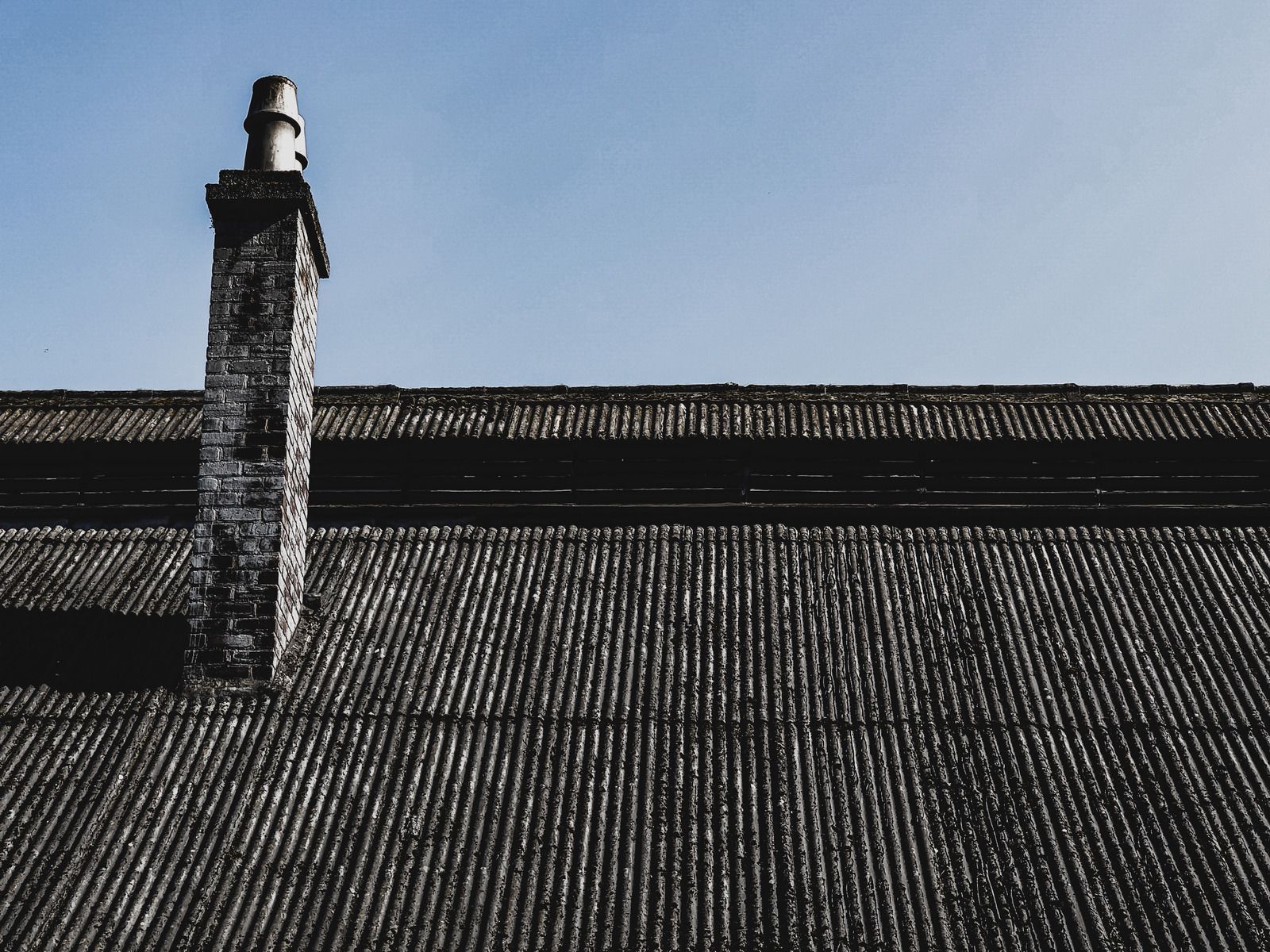 Roof with a chimney against a clear blue sky