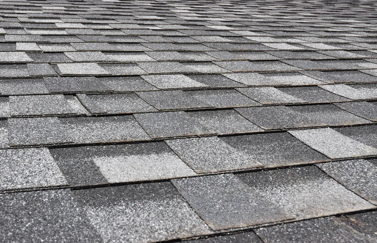 Close-up of gray asphalt roof shingles with a textured, overlapping pattern.