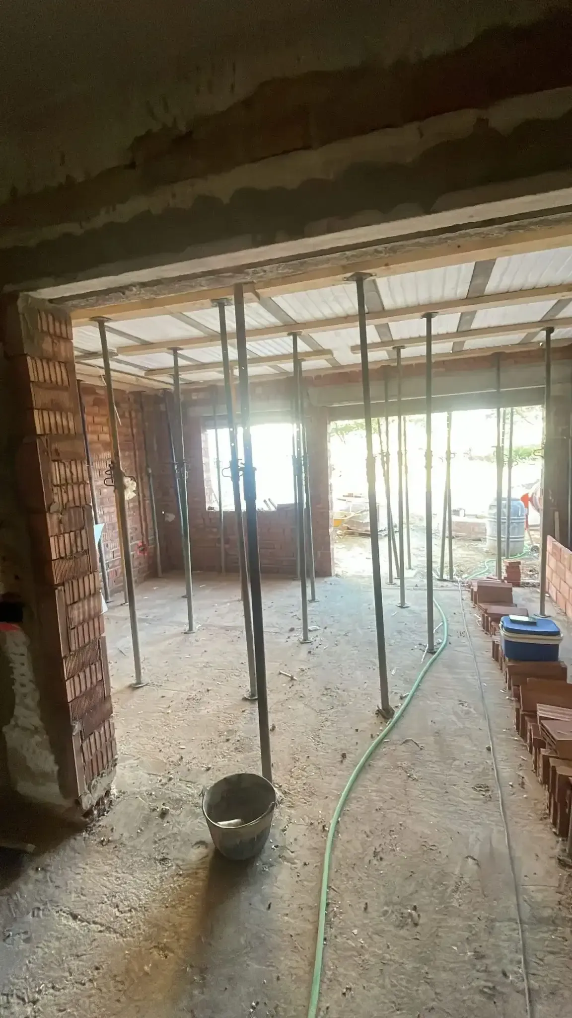 Interior de una casa en construcción con paredes de ladrillo visto, soportes metálicos
