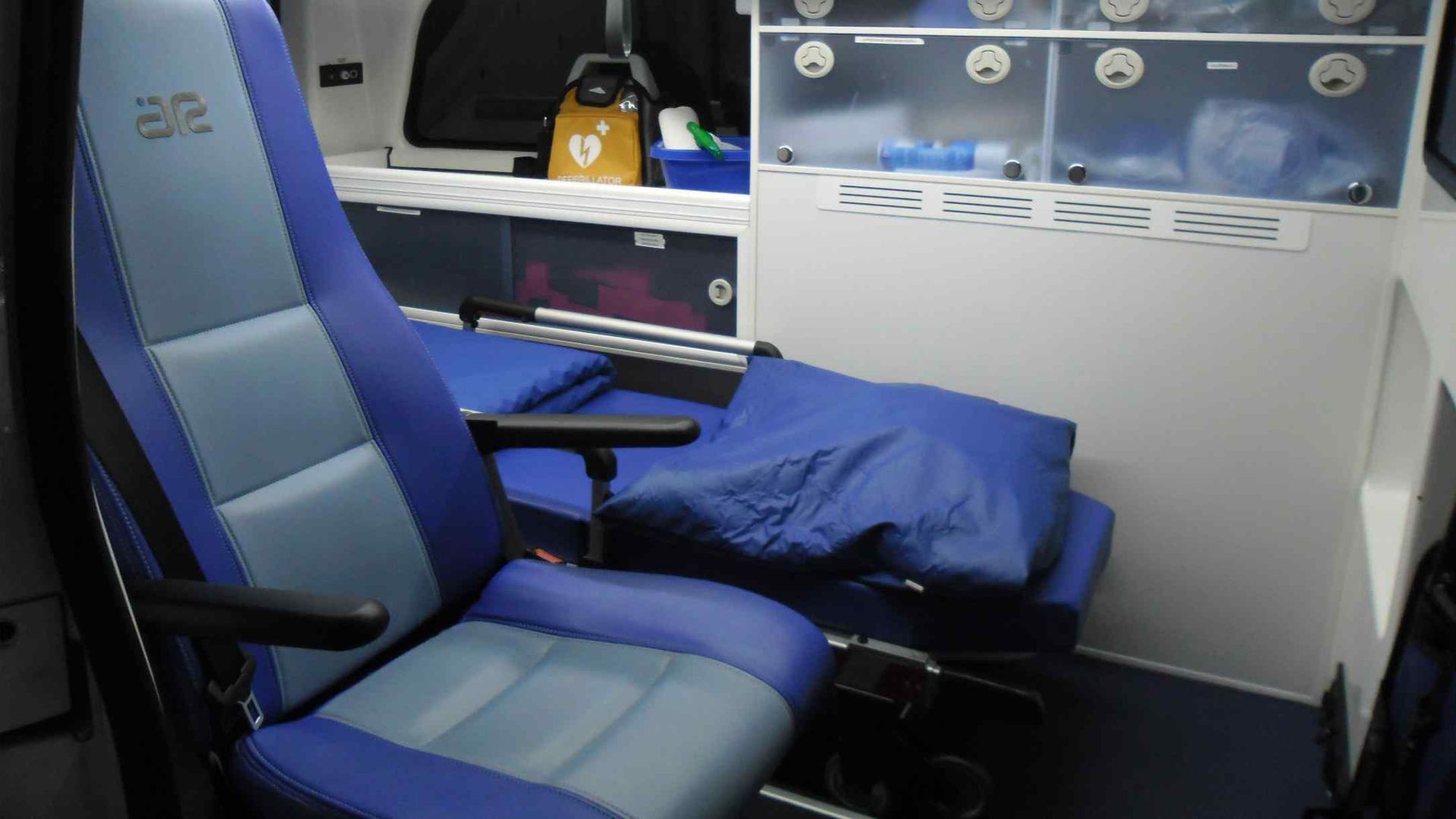 Siège inclinable bleu de type avion avec tablette et oreiller repliables dans un intérieur de cabine de voyage compact