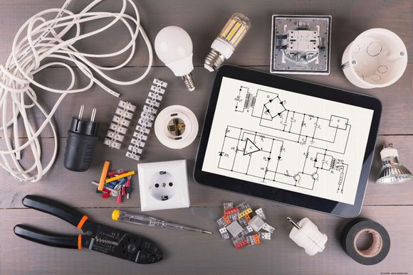 Elektrowerkzeuge Elektrowerkzeuge und Kabel liegen neben einer Schaltzeichnung auf einem Tisch.