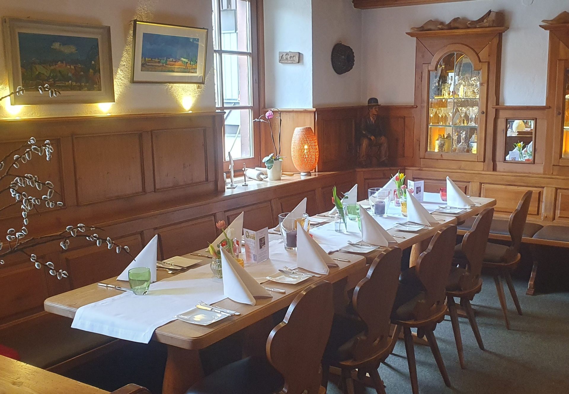 Elegantes Esszimmer mit einem langen, gedeckten Esstisch, Holzstühlen und warmem Wandleuchtenlicht