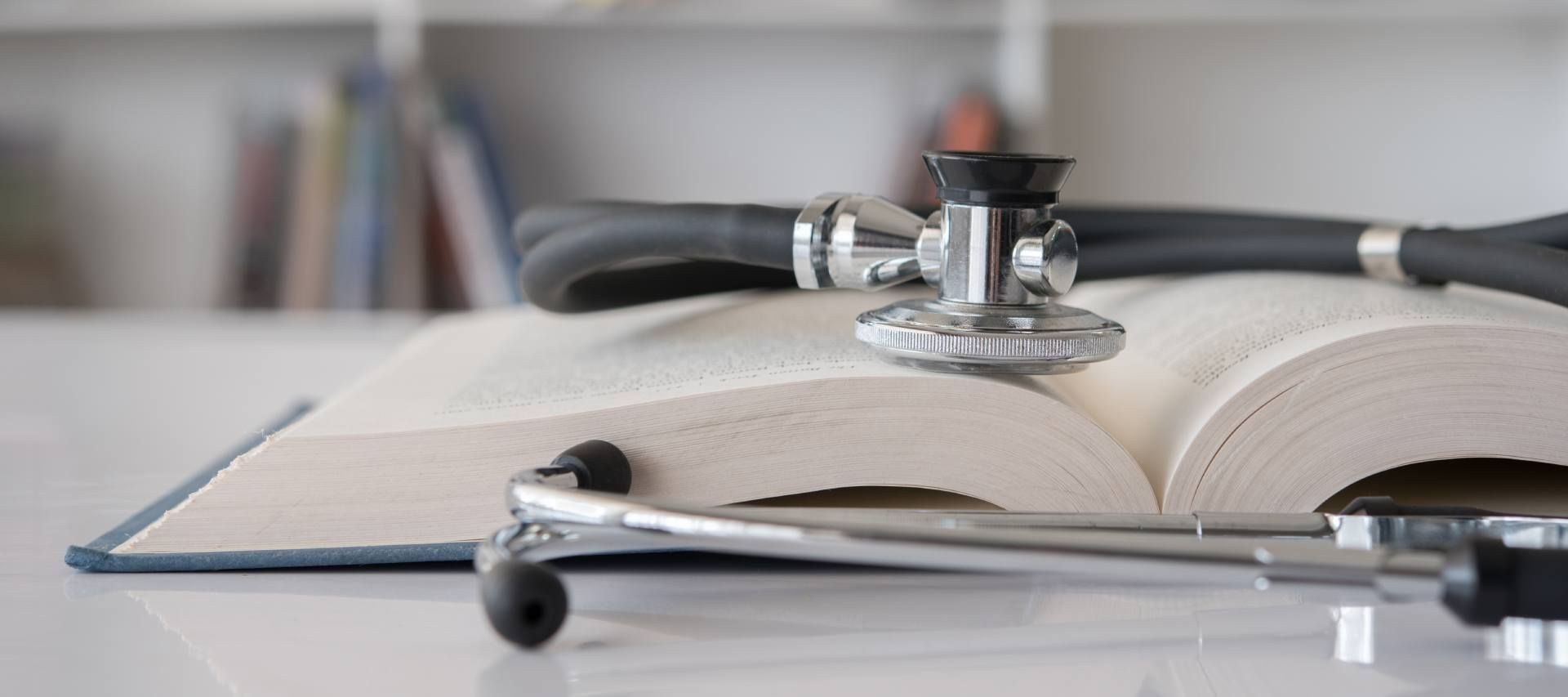In einem Krankenhaus hält ein Arzt mit verschränkten Armen ein Stethoskop.