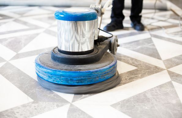 Una persona está usando una máquina para limpiar un piso de baldosas.