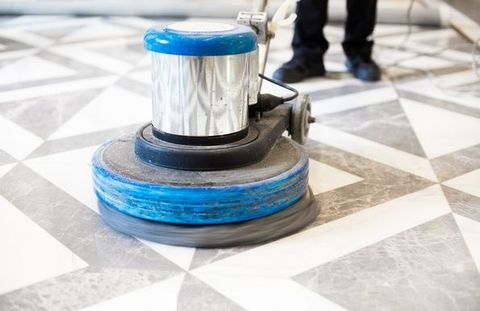 Una persona está usando una máquina para limpiar un piso de baldosas.