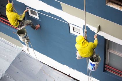 Zwei Maler streichen eine Wand blau