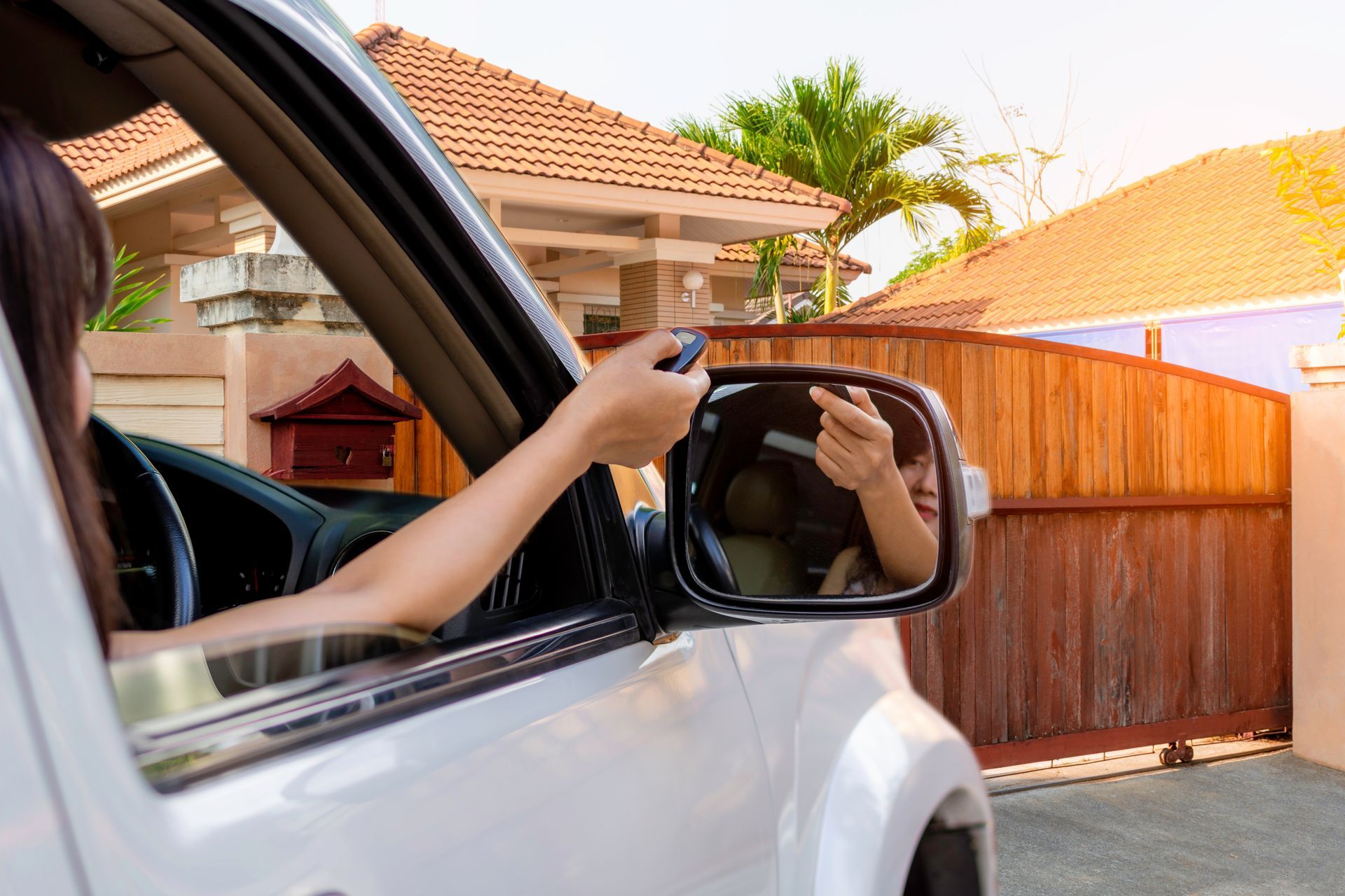 Femme en voiture, main utilisant la télécommande pour ouvrir une porte en bois automatique
