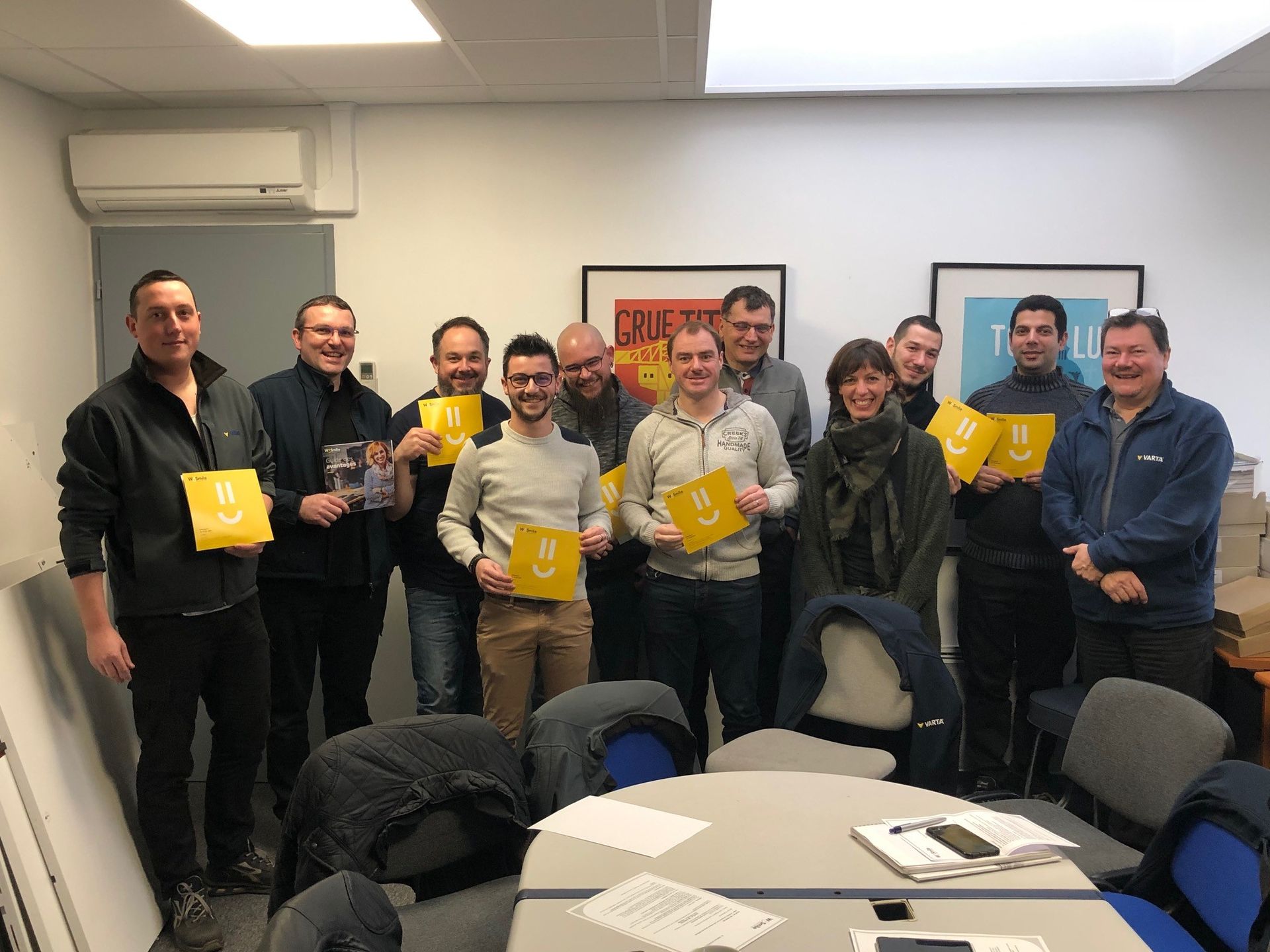 L'équipe de la société Atlantique Batterie tenant des pancartes smiley dans les mains