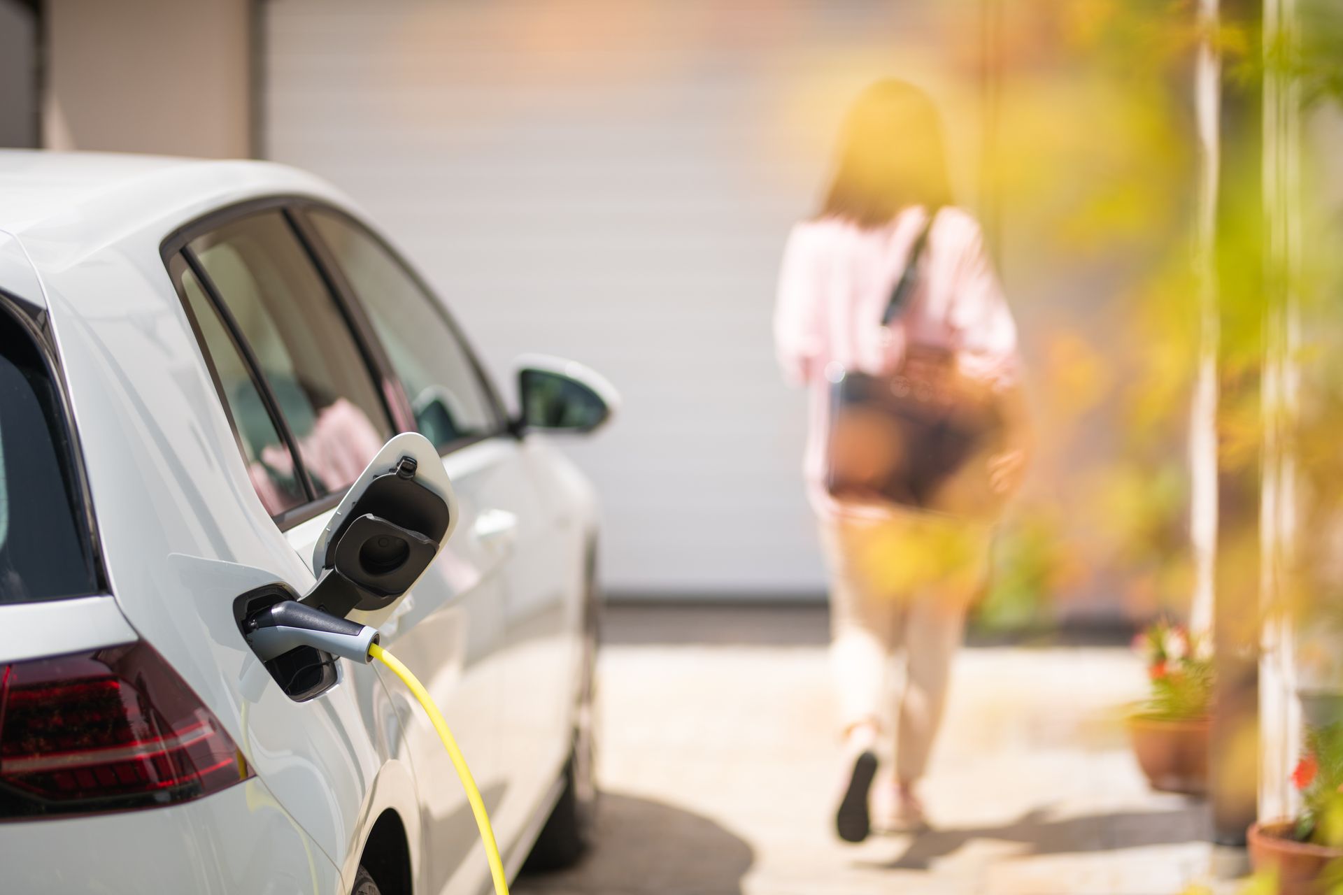 Gros plan d'un chargeur de voiture électrique avec silhouette féminine en arrière-plan
