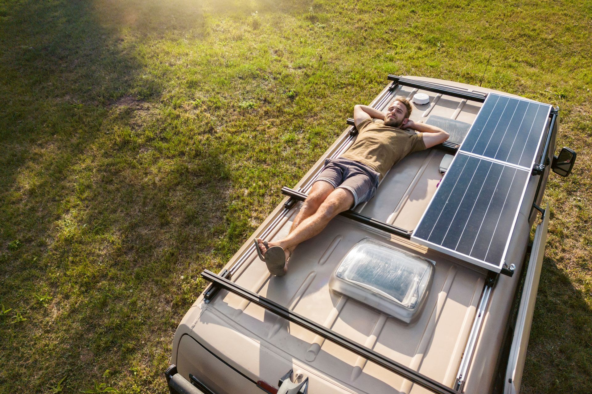 Un homme se détend sur le toit de son van à côté de ses panneaux solaires