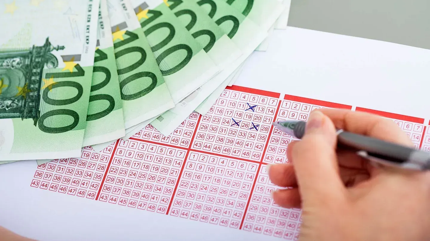 Una persona está escribiendo en un billete de lotería con un bolígrafo.