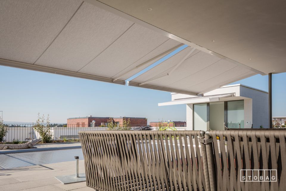 Über einem Zaun neben einem Pool hängt eine weisse Markise.