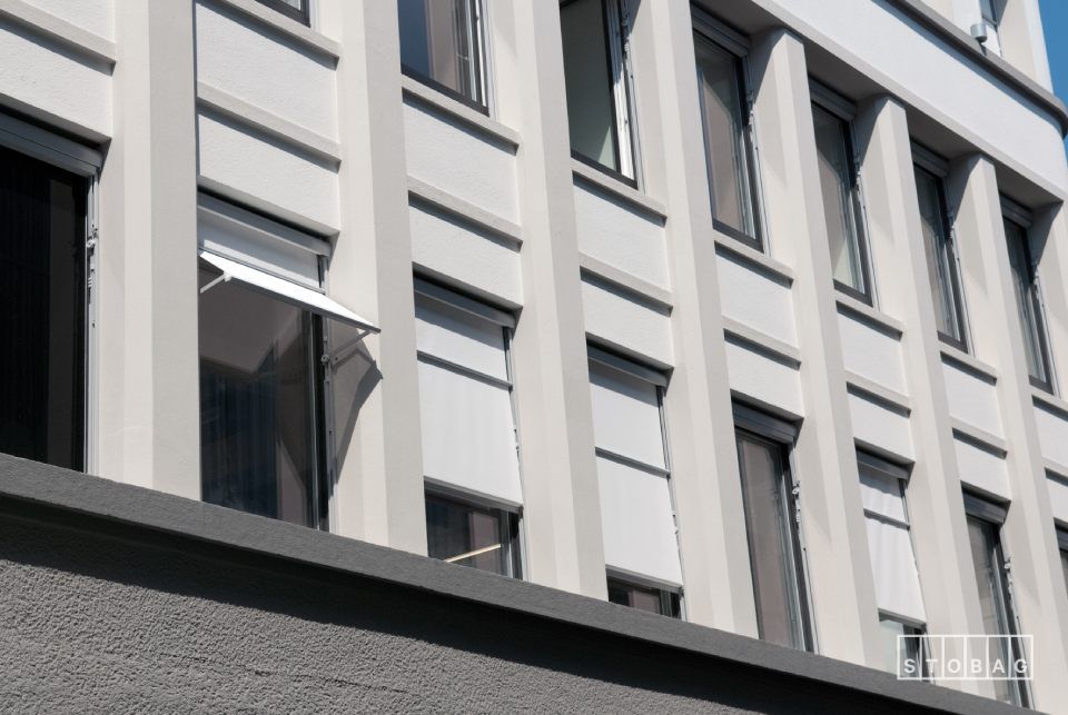 Ein Gebäude mit vielen Fenstern und einer Markise an der Seite