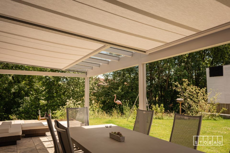 Eine Terrasse mit Tisch und Stühlen unter einem Baldachin.