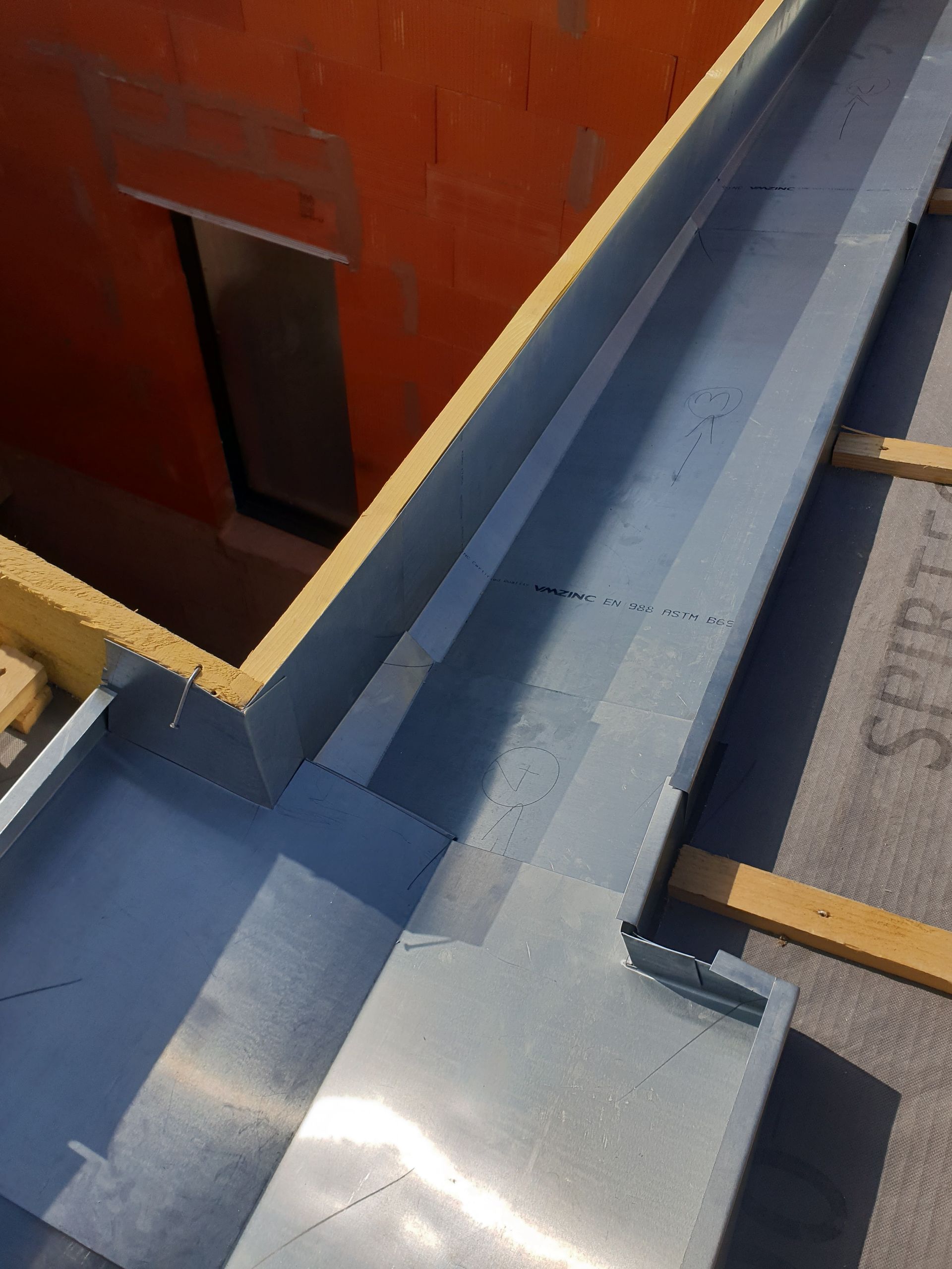 Des passerelles métalliques bleues sur le toit entourent une structure rouge percée d'une petite porte.