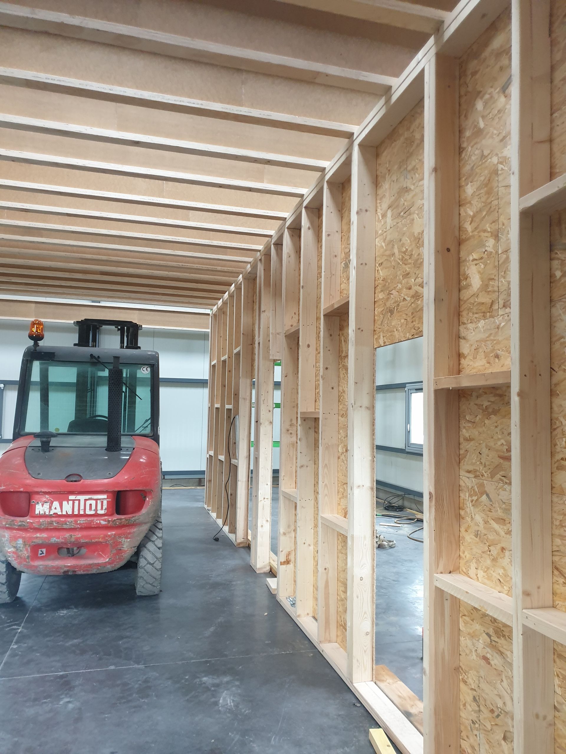 Chariot élévateur rouge dans une structure en bois à ossature bois en construction.