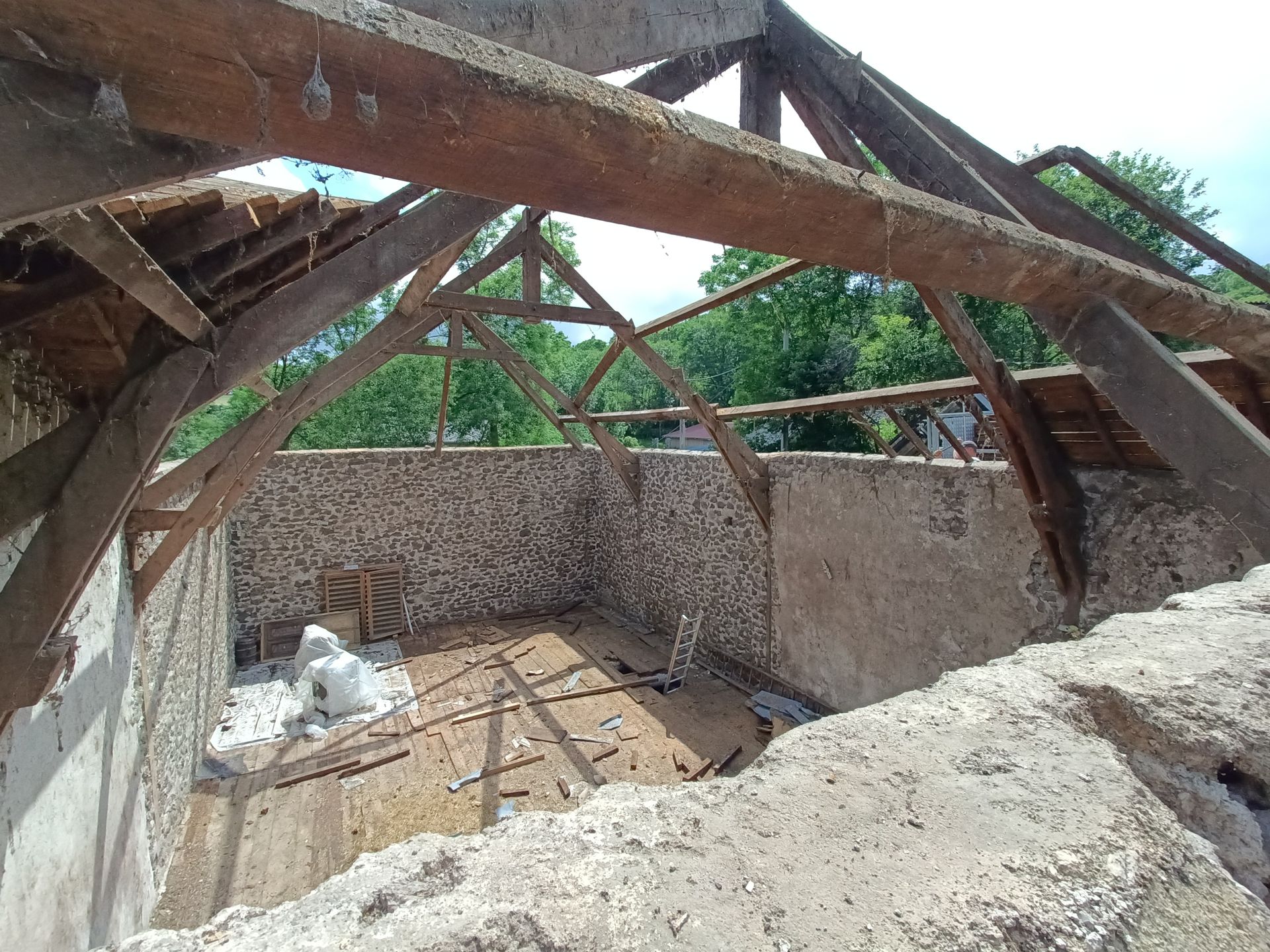 Toiture effondrée au-dessus de murs en pierre à l'intérieur d'un bâtiment endommagé.